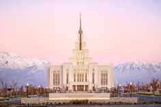 a large white building with a steeple on top and mountains in the back ground