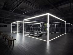 an empty gym with mirrors and treadmills in the center, all lit up by neon lights