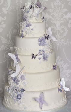 a three tiered wedding cake with purple butterflies on it