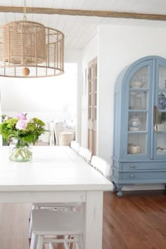 a dining room table and chairs with flowers in a vase on the center island, next to a china cabinet