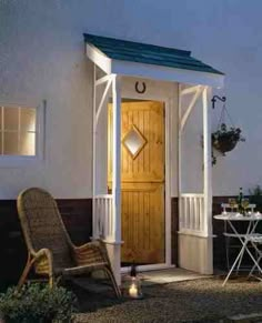 a small white house with a wooden door and chair in the front yard at night