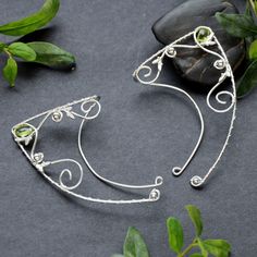 Elven ear cuffs/wraps made with sterling and fine silver and small peridot briolette.  The price is for a pair of cuffs. I can make variations with different stones, please message me. They are universal, lightweight and comfortable to wear - the shorter wire goes behind the ear and secures the wrap. You can slightly bend the wire to adjust it to your ear. Weight: 3,6 g 1 ear cuff Ear cuffs are totaly handmade and rhodium plated, so the silver does not tarnish. Whimsical Adjustable Wire Wrapped Ear Cuff, Adjustable Silver Whimsical Ear Cuff, Whimsical Adjustable Silver Ear Cuff, Adjustable Silver Elven Jewelry, Elven Style Silver Ear Cuff As Gift, Adjustable Silver Wire Wrapped Ear Climbers, Handmade Adjustable Elven Jewelry, Handmade Adjustable Sterling Silver Ear Climbers, Adjustable Sterling Silver Wire Wrapped Ear Cuff