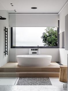 a large white bath tub sitting under a window next to a wooden step leading up to it