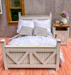 a bed with white sheets and pillows on top of a wooden floor next to a window