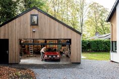 a man standing in front of a garage next to a red car