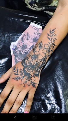 a woman's arm with flowers on it and a butterfly tattooed on the wrist