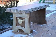 a bench that is sitting in the snow with a bird on it's side