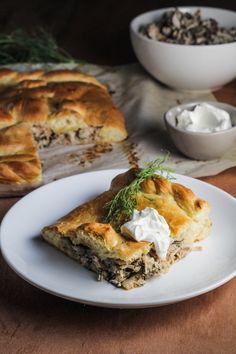 a piece of pie sitting on top of a white plate next to a bowl of yogurt