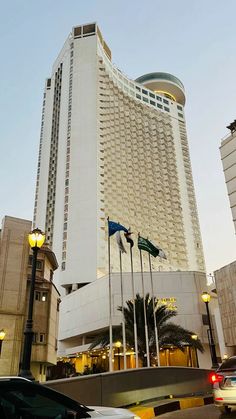 a tall white building sitting on the side of a road next to cars and traffic