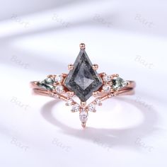 an engagement ring with a black diamond surrounded by white and green diamonds on the side