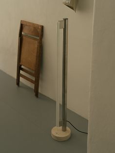 a chair sitting next to a wall with a phone on it's side and a pole in front of it