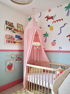 a baby's room with a pink canopy bed and wall decorations on the walls