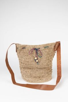 Make every day feel like a day at the beach with the crocheted Jute Bucket Bag with leather handles and accented with sea blue wooden beads on a cotton drawstring. Ethically handcrafted in small batches by environmentalist artisans with Prokritee, an organization in Bangladesh that provides jobs and skills training for women in under-resourced communities. Prokritee improves women's standard of living with safe jobs, fair wages, and the goal of self-reliance, helping mothers send their children Bohemian Crochet Bucket Bag For Travel, Bohemian Natural Bucket Bag For Daily Use, Bohemian Bucket Bag For Vacation In Natural Color, Everyday Bohemian Handwoven Bucket Bag, Bohemian Natural Bucket Bag For Vacation, Bohemian Handwoven Everyday Bucket Bag, Bohemian Bucket Bag With Braided Handles For Beach Season, Bohemian Natural Bucket Bag For Beach Season, Bohemian Shoulder Bag With Leather Handles For Beach Season