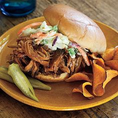 a pulled pork sandwich with coleslaw and potato chips