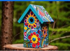 a colorful birdhouse sitting on top of a tree stump