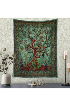 the tree of life tapestry is hanging in front of a wall with candles and vases