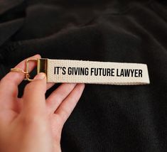 a person holding onto a white and black label that says it's giving future law