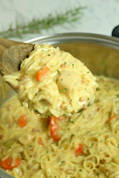 a wooden spoon full of macaroni and cheese with carrots on it,