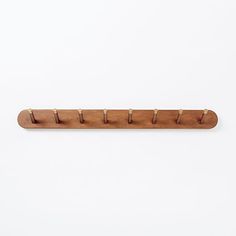 a wooden rack with five pegs on the top and one in the middle, against a white background