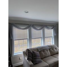 a living room filled with furniture and two windows covered in shades on the same window sill