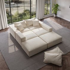 a large white couch sitting on top of a rug in a living room next to a window