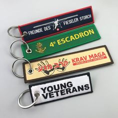 four keychains with different colors and designs on them, one has a name tag that says young veterans