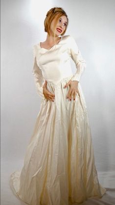 a woman in a long white dress posing for a photo with her hands on her hips