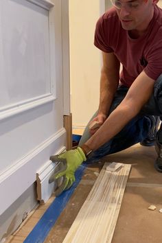 a man in red shirt and green gloves working on a door frame with a pair of scissors