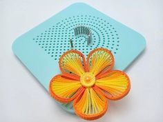 an orange and yellow flower is on top of a blue speaker with a wire attached to it