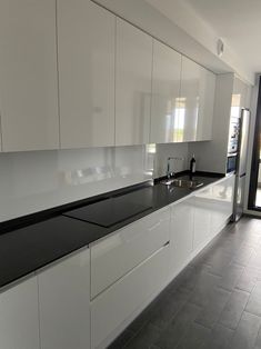 an empty kitchen with white cabinets and black counter tops on the walls, along with a sliding glass door that leads to a patio