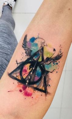 a watercolor style harry potter tattoo on the right arm and shoulder, with colorful ink splatters all over it