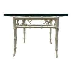 a white table with glass top and bamboo decoration on the legs, against a white background