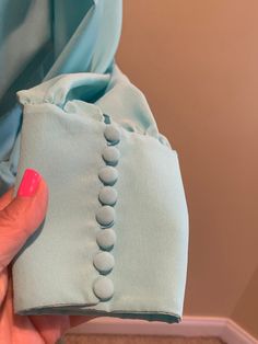 "Beautiful details on this flowy 1980s wrap style blouse. Light blue in color with gathers on the shoulders. Puffy sleeves, with fabric covered buttons and loops on the cuffs. Tie waist. Shoulder pads. There is a hook and eye closure on the bust - however the \"eye\" is a thread loop, it seems to do the job well. No manufacture tags. I estimate it to be a size small, around a size 6. It is shown and a size 6 dress warm with a 34 inch bust and a 26 inch waist. The bust measures 19 inches from arm Blue Bishop Sleeve Blouse For Spring, Chic Blue Blouse With Gathered Sleeves, Spring Blue Blouse With Gathered Sleeves, Blue Blouse With Gathered Sleeves For Spring, Blue Bishop Sleeve Blouse, Blue Puff Sleeve Top With Button Closure, Blue Blouse With Bishop Blouson Sleeves, Elegant Blue Blouse With Gathered Sleeves, Blue Blouse With Pleated Sleeves For Spring