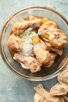 raw chicken in a glass bowl with spices and seasoning