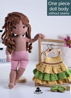 a crocheted doll standing next to a dress