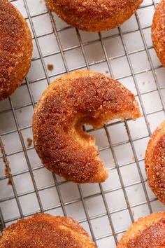 several sugary donuts on a cooling rack with one partially eaten doughnut in the middle