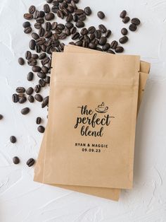 two brown bags filled with coffee beans on top of a white table next to each other