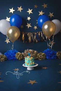 a blue and gold birthday cake surrounded by balloons