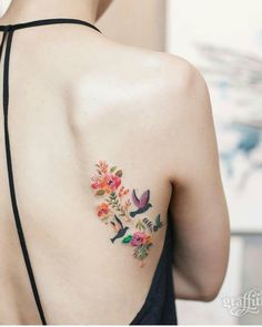 the back of a woman's shoulder with flowers and birds tattoo on her left side