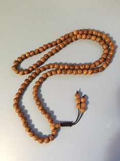 "Bodhi seed mala necklace made of 108 12mm beads with a Bodhi seed guru bead and an adjustable knot that allows you to change the length and tightness of the beads. Bodhi seeds are usually not polished so they are a solid color with small ridges or veins. Bodhi in Sanskrit translates to \"enlightened\" or \"awakened,\" therefore the Bodhi seed means \"enlightened seed.\" Bodhi is also a term in Buddhism to reflect a Buddha's understanding of the true nature of things. Many Buddhist wear the Bodh Holistic Necklaces With 8mm Beads For Festivals, Spiritual Beaded Necklace With 108 Beads For Festivals, Spiritual Beaded Necklace For Festivals, Adjustable Spiritual Beaded Necklaces For Rituals, Holistic Wooden Beads For Festivals, Wooden Beads Necklace For Meditation And Festivals, Holistic Wooden Beads Mala For Festivals, Wooden Beads Necklaces For Meditation And Festivals, Spiritual Wooden Beads Necklace For Puja