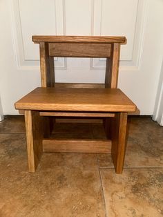 a wooden step stool sitting on top of a tile floor next to a white door