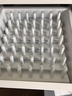 a bunch of white candles sitting inside of a glass container