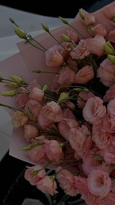 a bouquet of pink flowers sitting on top of a white car parked in front of a building