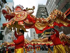 two men in red and gold costumes are performing on the street with large dragon decorations