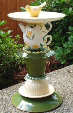 a stack of tea cups sitting on top of each other in front of some bushes