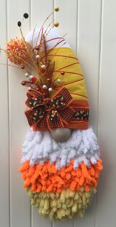 an orange, yellow and white hat hanging on the side of a door with decorations around it