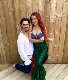 a man and woman pose in front of a wooden fence