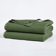 two folded green towels sitting on top of each other in front of a white background