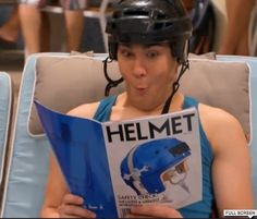 a man wearing a helmet and holding a book in his hands while sitting on a chair