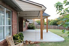 a covered patio with a chair and fire pit in the back yard next to it